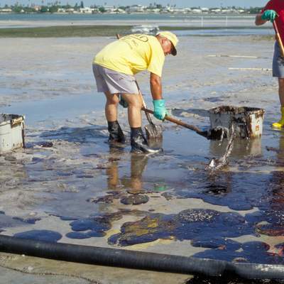 Hombres limpiando derrame de petróleo en la playa